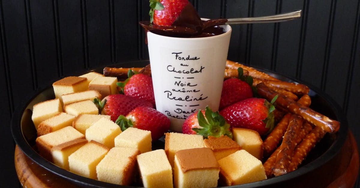 How to keep a chocolate fondue in a liquid form? - White Ceramic Mug on Top Sppon and Strawberry Surrounded Leche Plan and Strawberry on Black Round Shape Tray