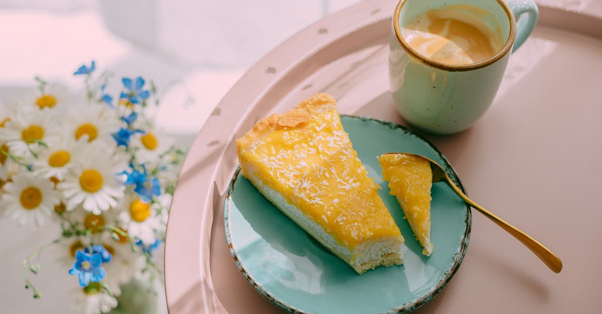 How to keep baked seitan from being too tough? - From above of delicious latte coffee in ceramic mug and slice of cheese cake on plate served on tray and bunch of field flowers on table