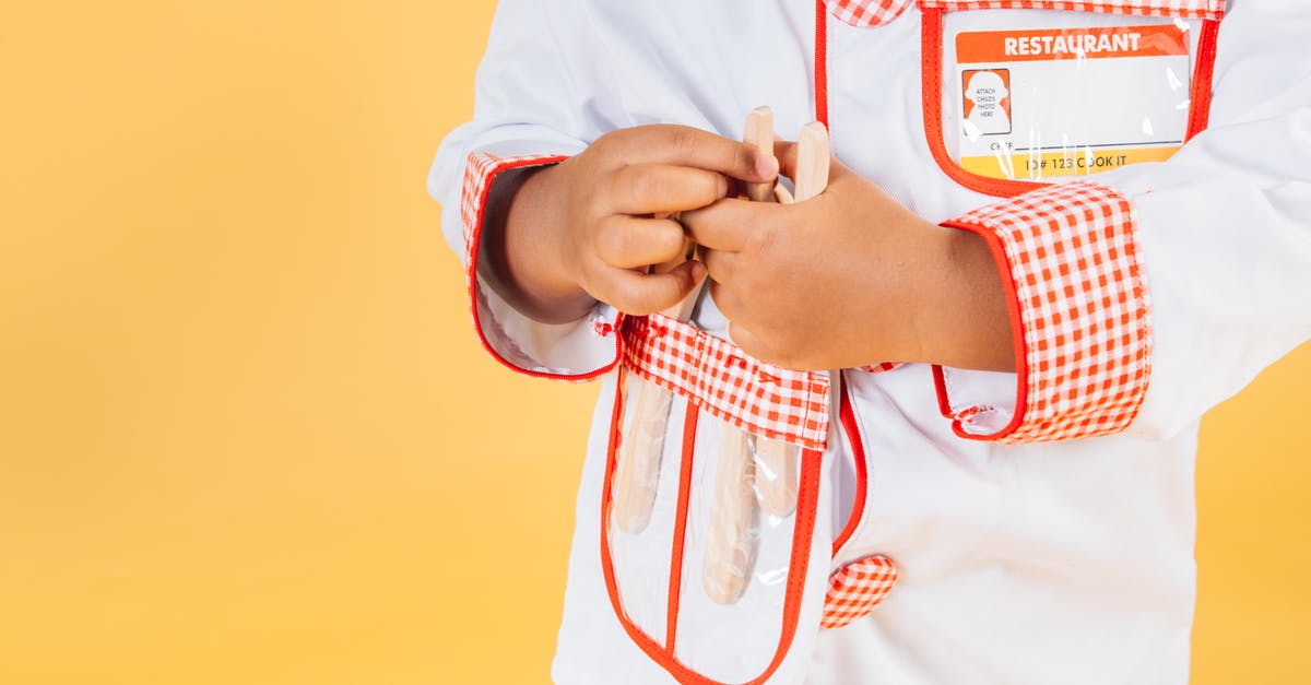 How to learn to cook? [duplicate] - Crop anonymous ethnic kid with supplies for kitchen wearing chef jacket in studio against yellow background