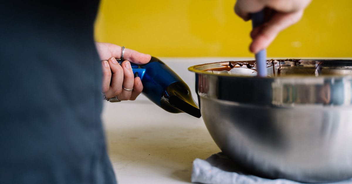 How to lower the melting point of a specific chocolate? - Person Holding a Hair Dryer while Mixing the Stainless Steel Bowl 