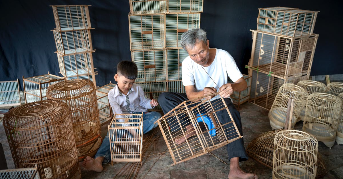 How to make Chinese-style cornstarch coating stick - Aged ethnic craftsman with gray hair creating handmade souvenir bird cages while little grandson helping and picking wooden bamboo sticks