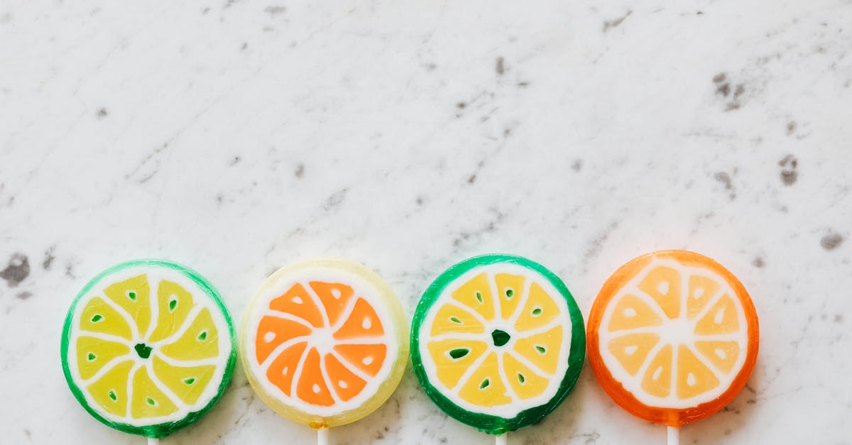 How to make hard candy with only fruit as a sweetener - From above of bright round shaped candies with creative decoration inside on thin plastic sticks on marble surface