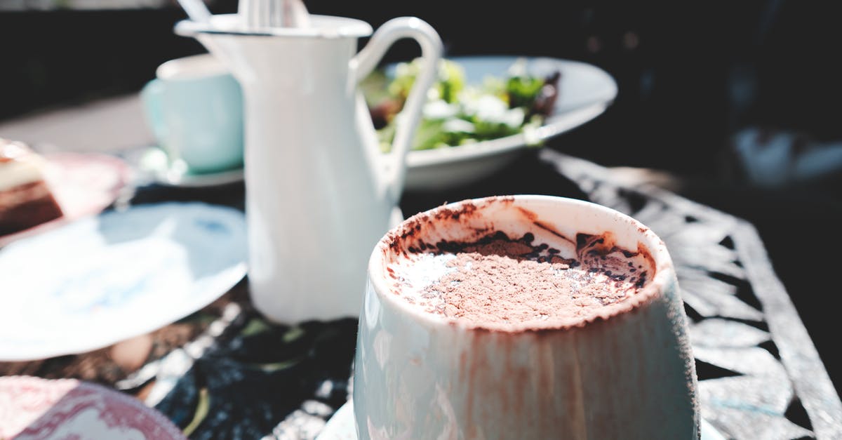 How to make Instant Hot Chocolate Taste Less Watery - Tasty fresh hot chocolate in white cup served on metal table with fresh salad on sunny weather