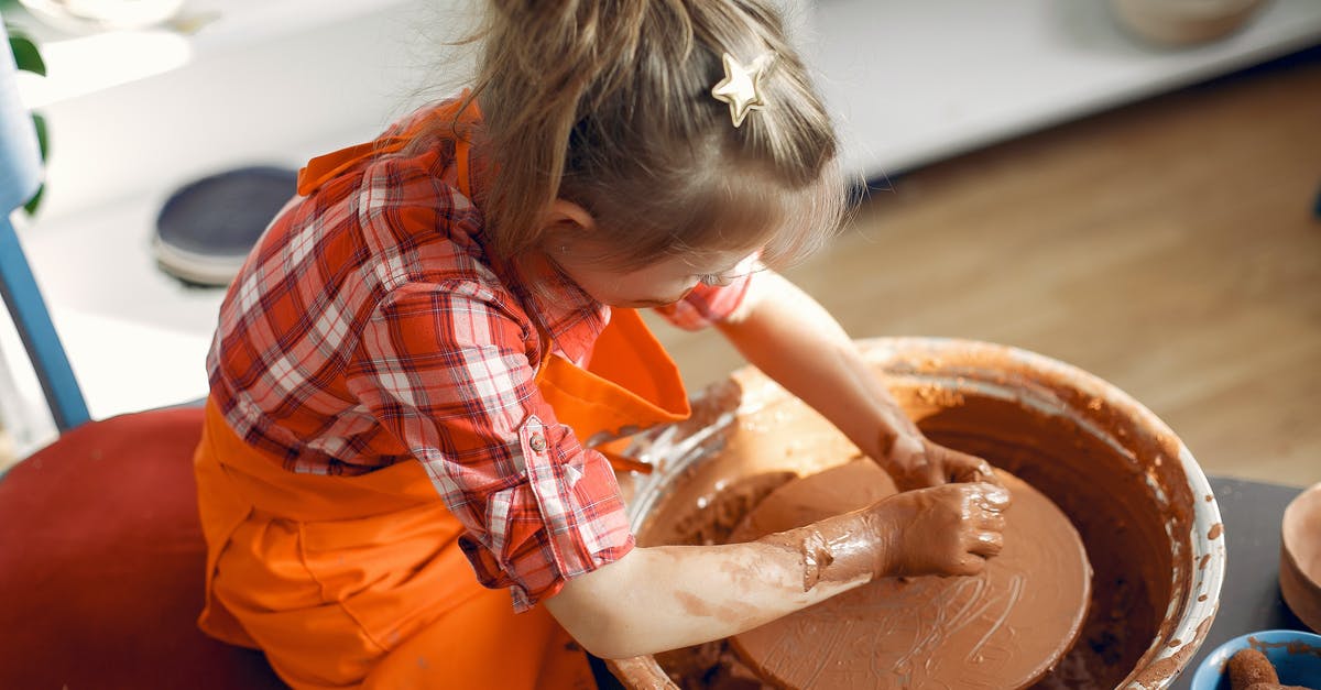 How to make potato wheel not stick to mold - From above  anonymous little girl in red check shirt and apron working with clay on pottery wheel while spending time in workshop