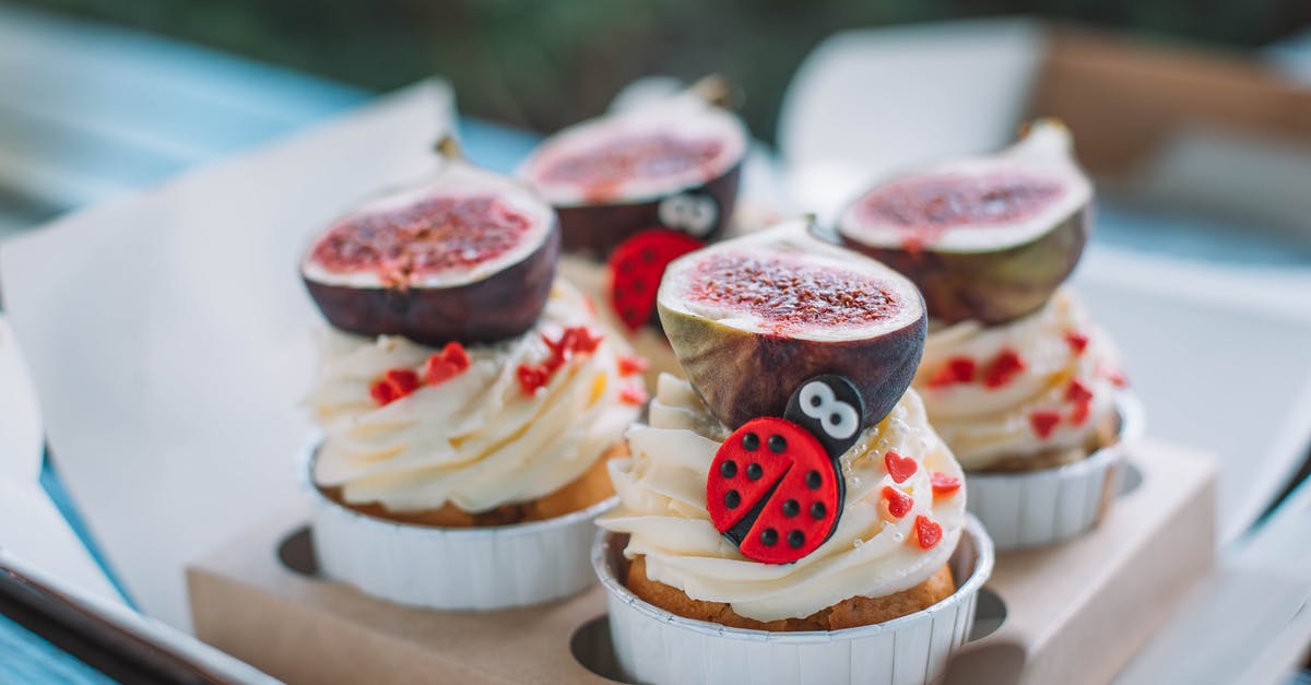 How to make smooth ice cream flavored with fresh fruit? - Tasty cupcakes with white frosting decorated with fresh cut figs and sprinkles placed in package on table against blurred background