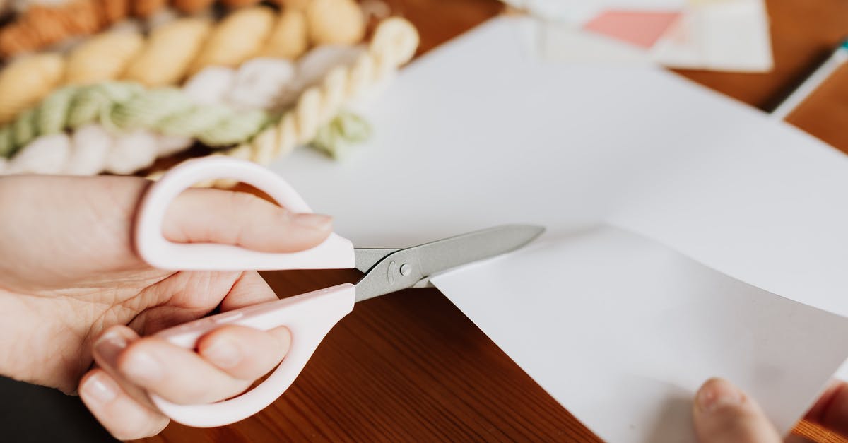 How to make use of old apples? - Crop young woman cutting paper sheet on wooden table