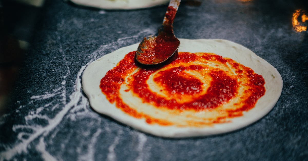 How to measure tomatoes for making sauce? - Close-Up Shot of Person Spreading Tomato Sauce onto Pizza Dough