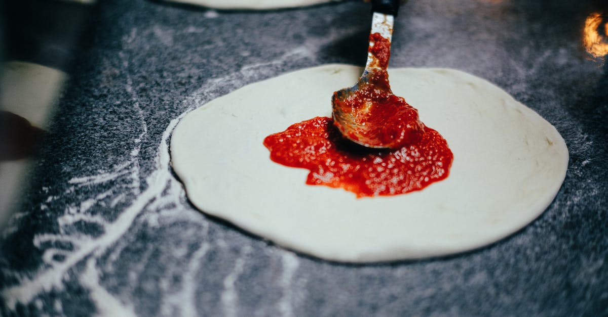 How to measure tomatoes for making sauce? - Close-Up Shot of Person Spreading Tomato Sauce onto Pizza Dough