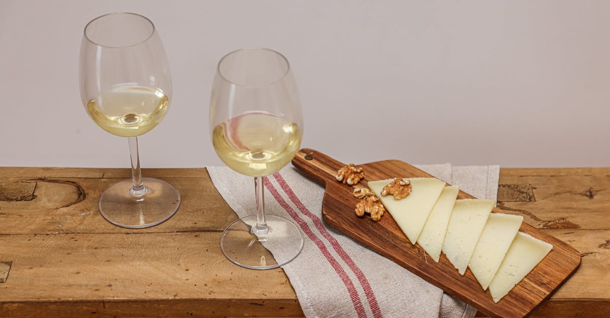 How to pair cheese with wine? - Glasses of Wine beside Walnuts and Slices of Cheese on a Wooden Chopping Board