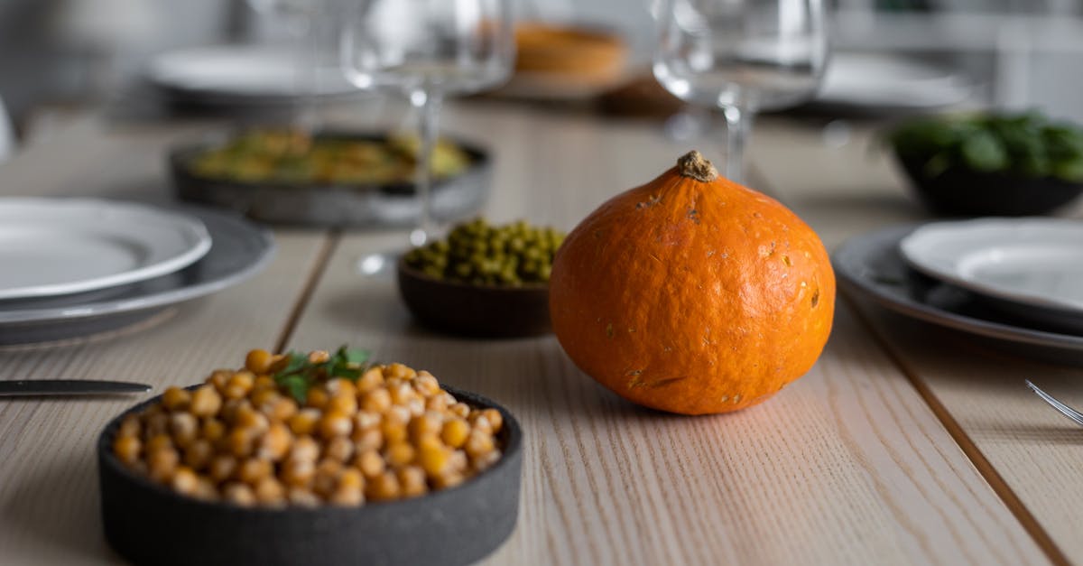 How to Prepare Chickpea Purée from a Can? - High angle of wooden table served with delicious chickpeas and fresh ripe pumpkin near empty plates and glasses for guests