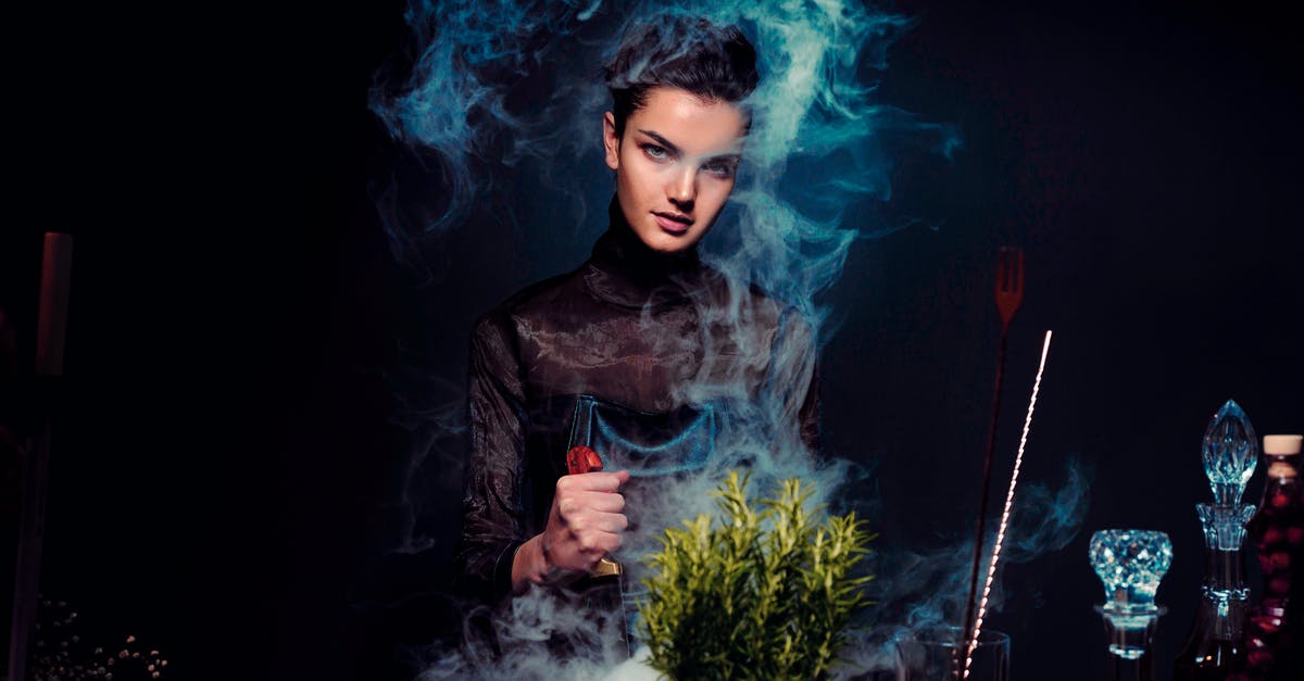 How to prepare cockles for cooking? - Graceful young female alchemist with knife in hand in black outfit preparing potion from various herbs among smoke in dark room