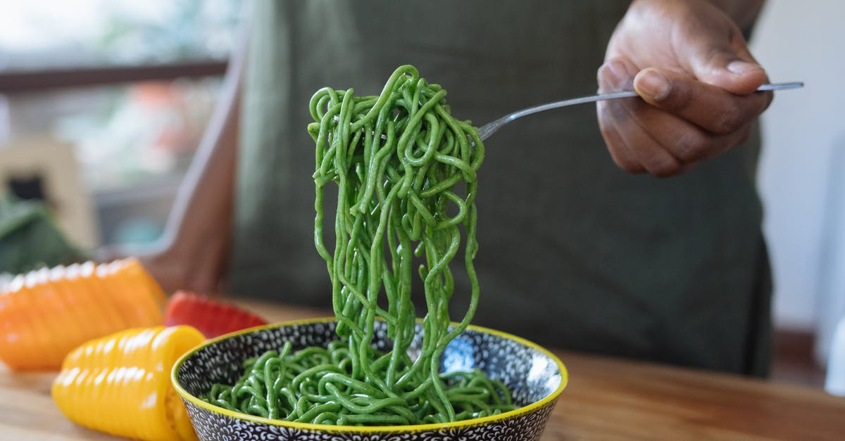 How to prepare shirataki noodles to more closely resemble classic pasta? - Person Holding Stainless Steel Fork With Green Noodles in  Blue Ceramic Bowl