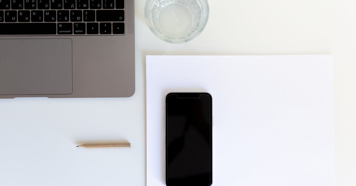 How to prepare soup for an office potluck? - From above of smartphone placed on white paper with laptop and glass of water preparing for working day in modern workplace