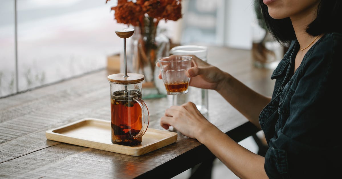 How to prepare tasty tea on induction cooktop? - Crop woman enjoying herbal tea at high table