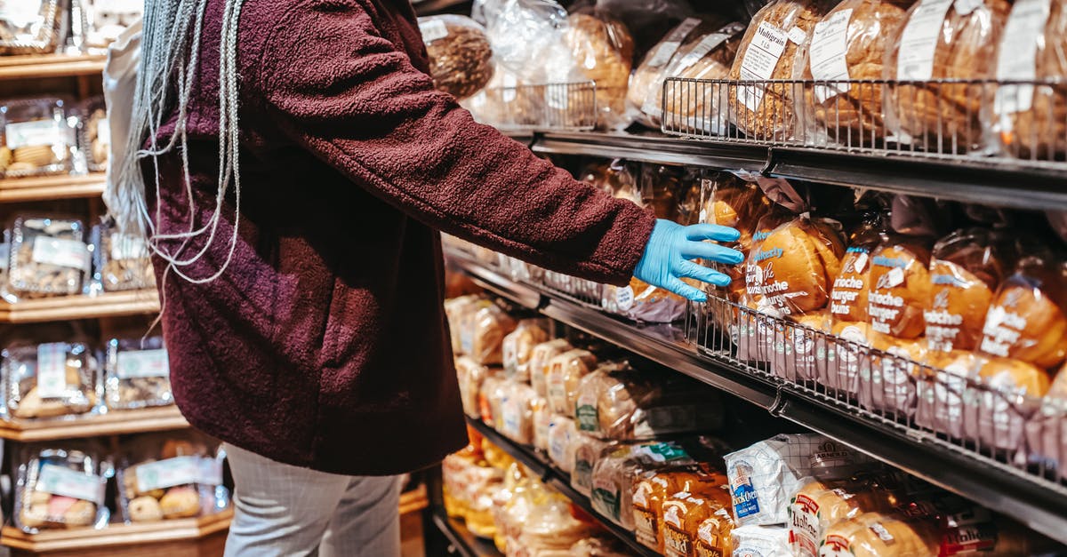 How to prevent bread sticking to cast iron pan? - Side view of crop anonymous female customer picking loaf of bread in supermarket during coronavirus epidemic