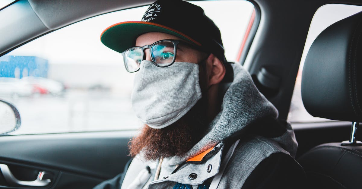 How to prevent flies sticking to hood fan lightbulb guard? - Young bearded hipster in glasses and protective mask wearing warm clothes and cap while sitting in car and looking away