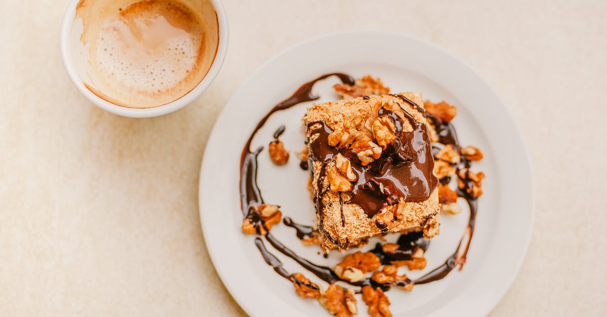 How to prevent homemade soy milk separating in hot tea? - Top view of delicious homemade dessert with chocolate glaze topped with walnuts and cup of fresh cappuccino with froth