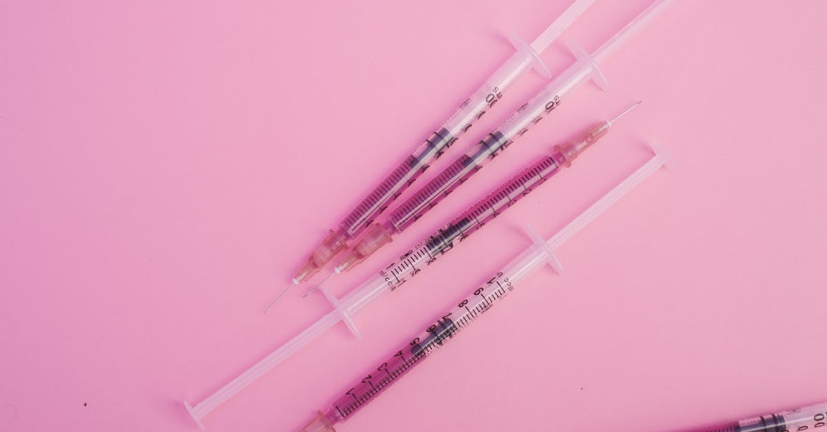 How to prevent liquids from spilling when pouring from measuring cup? - From above of syringes with needles filled with purple substance placed on pink background