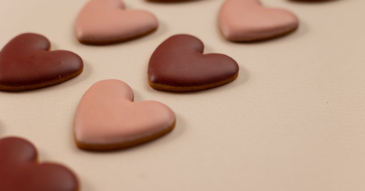 How to prevent sweet thick glaze/sauce from setting after cooling? - From above of red and pink heart shaped cookies with frosting arranged in rows on beige background during valentines day