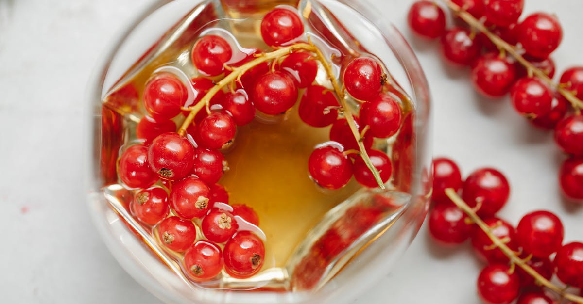 How to properly clean a whiskey flask? - From above of strong aromatic alcoholic drink served with fresh red currant placed on white table