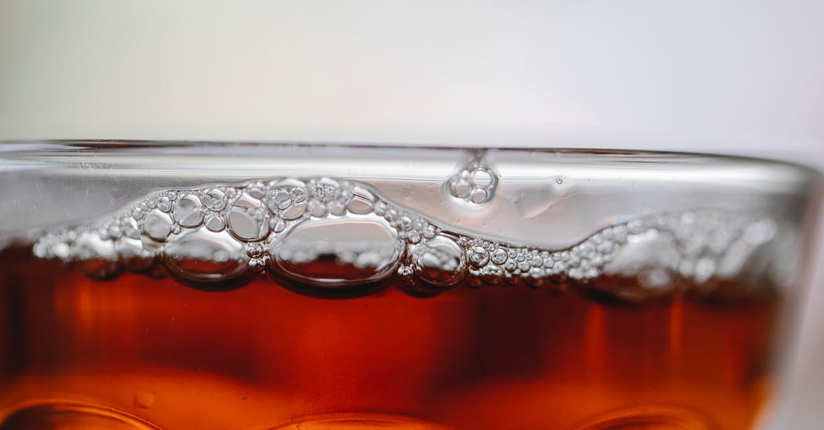 How to properly clean a whiskey flask? - Closeup of alcoholic drink with small bubbles in clean transparent glass on white background