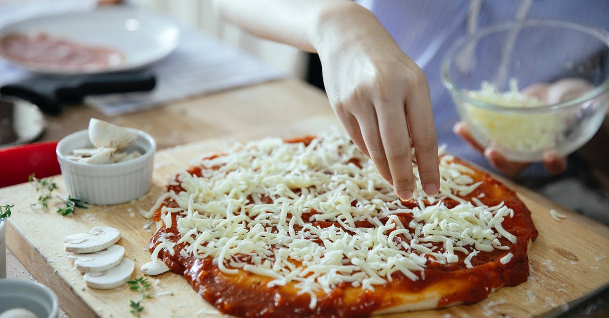 How to put mushrooms in soup/stew without creating foam? - From above of crop anonymous female adding cheese from bowl on uncooked yummy pizza with tomato sauce  on wooden table in kitchen