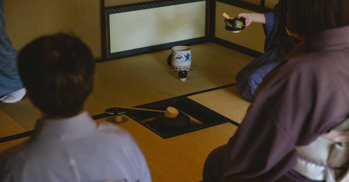 How to recover a cast-iron pot? - Anonymous group of people wearing authentic robe sitting near bamboo ladle on iron pot and dishware for traditional Japanese ceremony