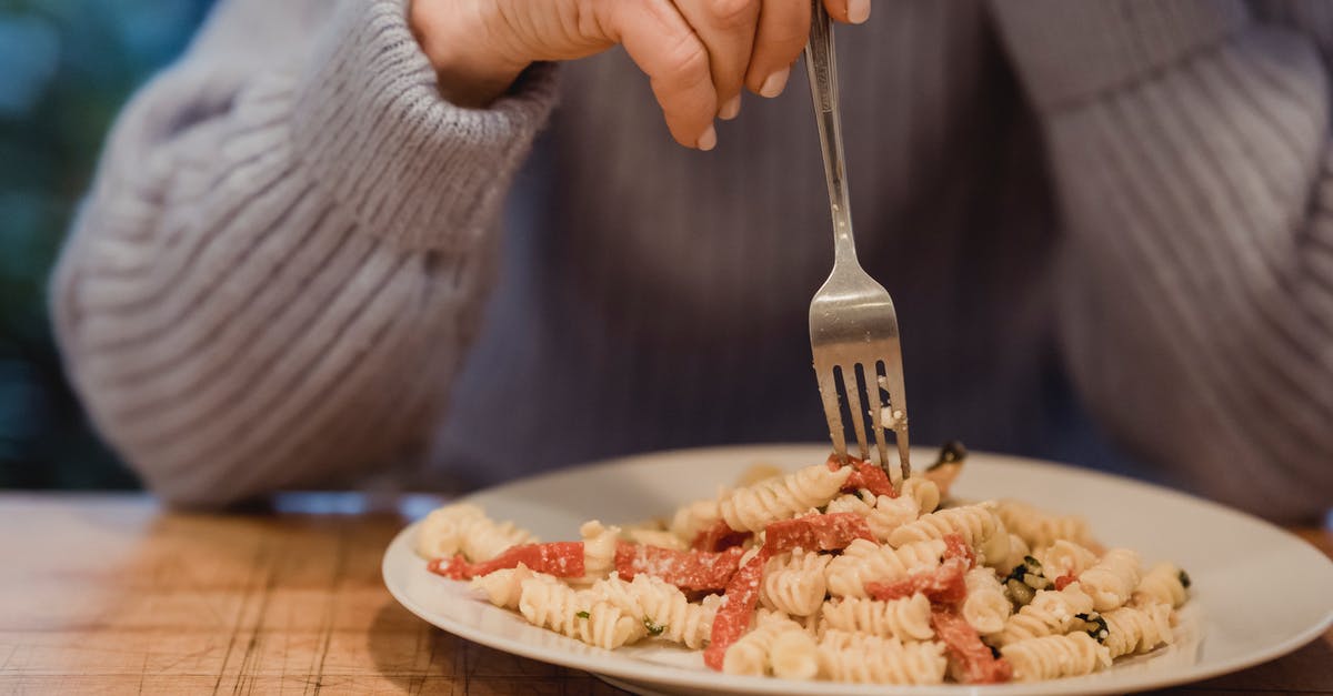 How to reduce the bitter taste in broccoli rabe - Crop faceless female wearing blue sweater enjoying delicious fusilli pasta with tomatoes and broccoli served on white plate