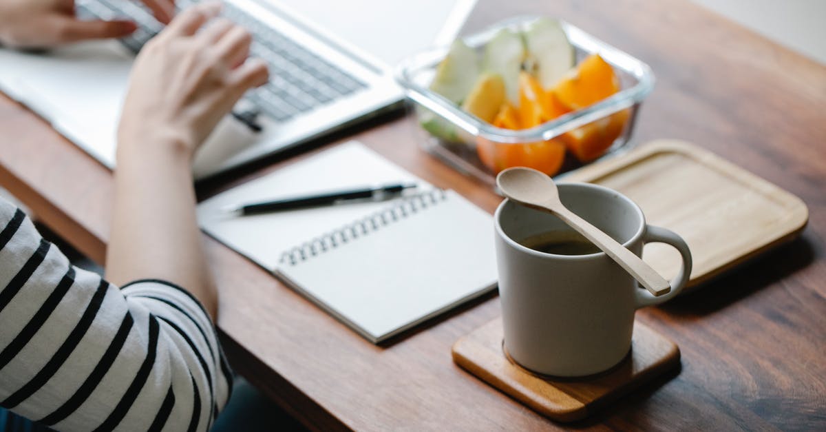 How to reduce the flavour of orange zest in chicken? - Crop anonymous remote employee working on netbook at table with mug of hot drink and eco friendly spoon