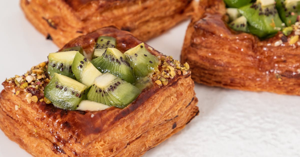 How to reduce the sweetness of a cake recipe without reducing the sugar [closed] - Closeup of golden baked puff pastries with glazed kiwi cubes and crushed nuts