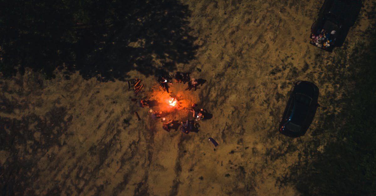 How to remove commercial seasoning from skillet? - Drone view of group of friends spending time together by flaming bonfire in woodland at night