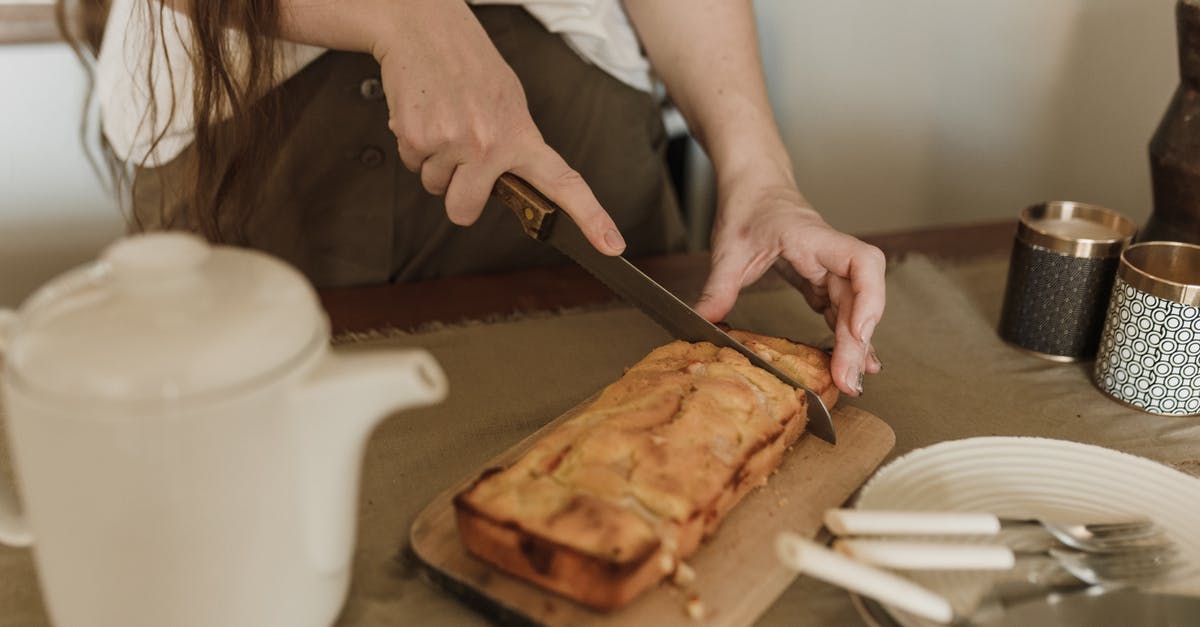 How to remove hardened dough from hair? - Crop anonymous female with long dark hair in casual clothes cutting appetizing sweet banana bread while standing at table in kitchen