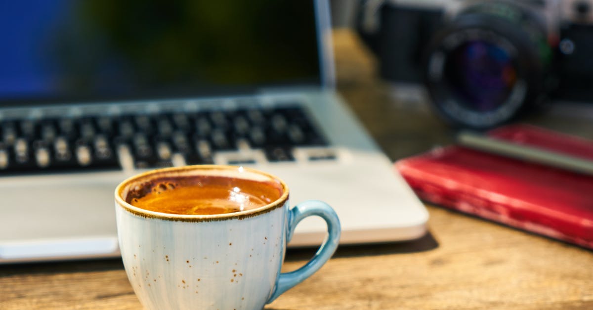 How to remove residual flavours from, e.g., a coffee press - A cup of coffee and a camera on a wooden table  in the workplace
