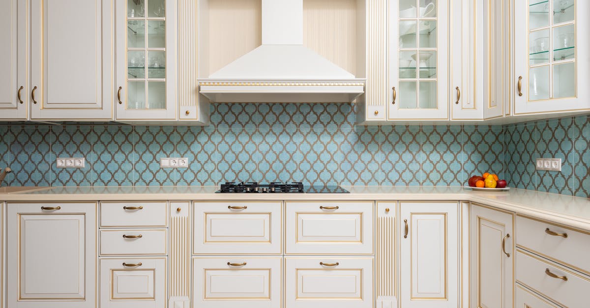 How to remove white stain after stove cleaning? - Interior of light modern kitchen with wooden white cabinets and blue tile backsplash with classic hood