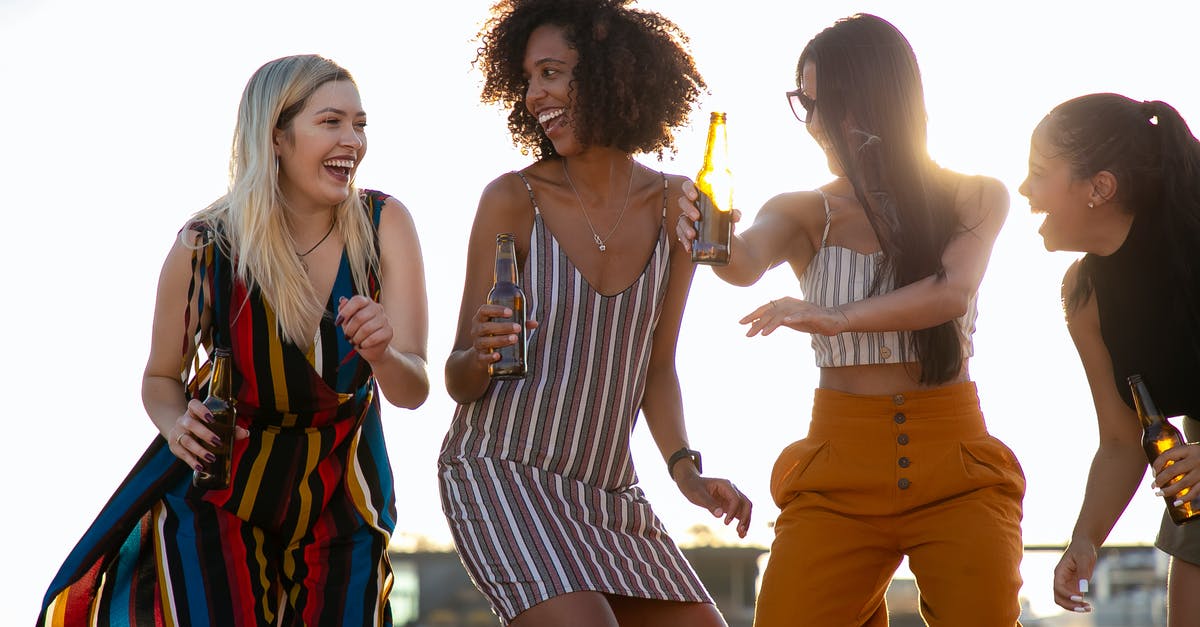 How to replace booze in eggnog? - Group of cheerful young multiracial ladies laughing and dancing with beer bottles in hands during summer party on rooftop on sunny day