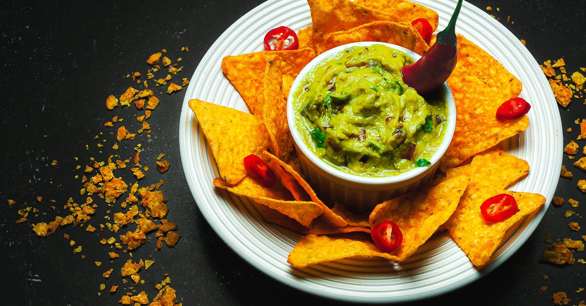 How to replace polenta in Mexican Polenta Casserole recipe - From above arrangement of yummy guacamole bowl surrounded with crispy nachos and decorated with chili pepper while served on black table