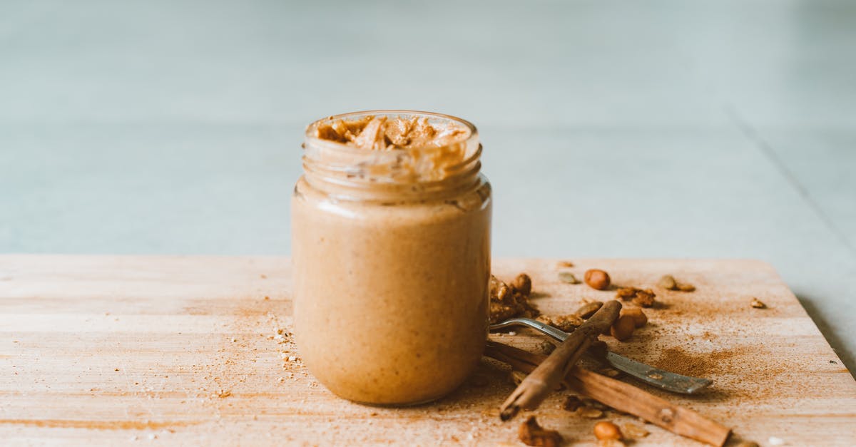 How to salvage hardened peanut butter from jar bottom - Clear Glass Jar With Brown Liquid on Brown Wooden Table