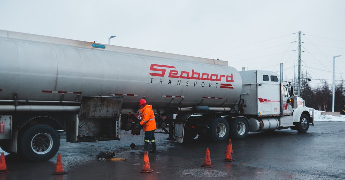 How to saute without oil on stainless steel pots/pans? - Back view of anonymous male worker in bright uniform and helmet cleaning oil truck vehicle while standing on asphalt roadway surrounded by barriers under white sky in town