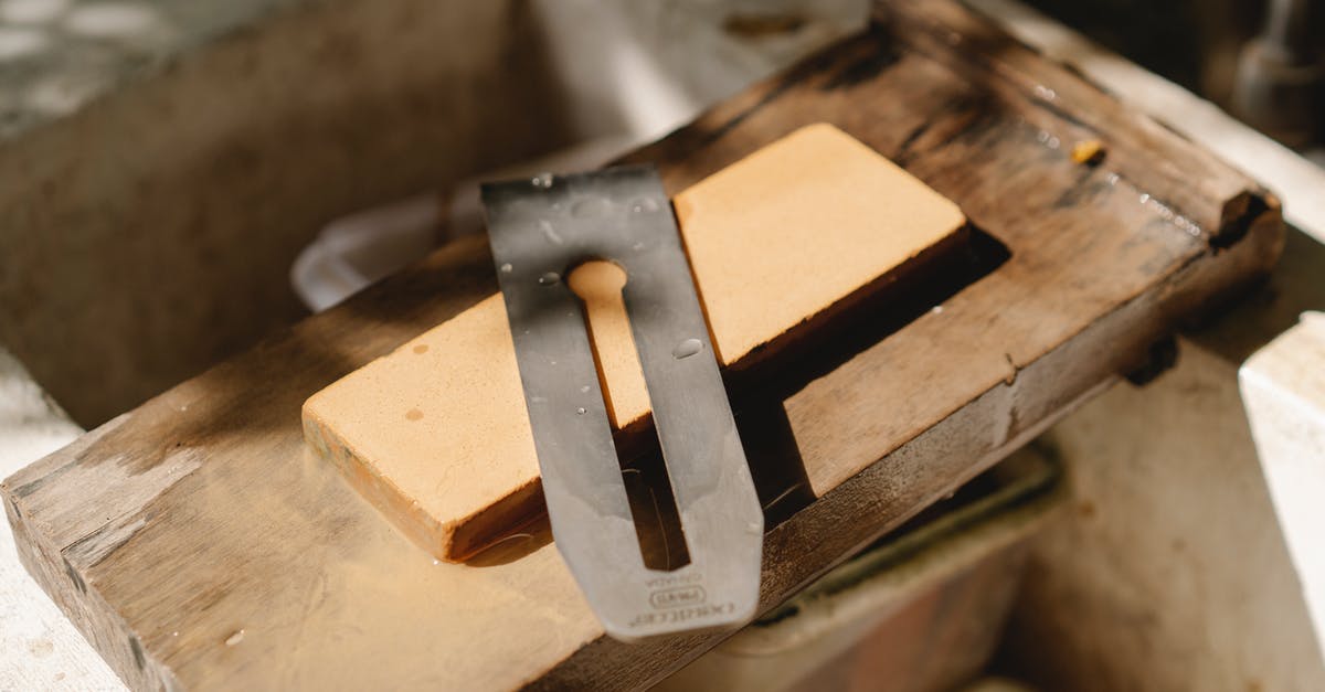 How to stop steel cut oats from burning? - From above of sharp knife from jointer for cutting wood placed on wooden plank in professional studio on blurred background