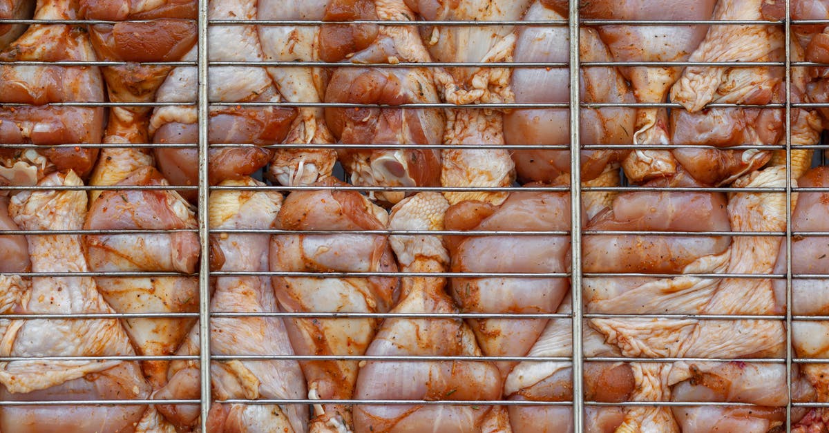 How to stuff and/or spice the chicken BELOW the skin? - Top view background of raw chicken drumsticks with skin and condiments under metal rack in daytime