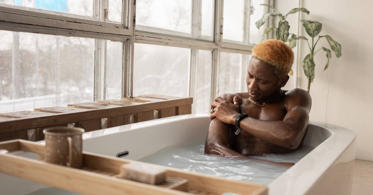 How to take care of a wooden mortar and pestle? - Young African American man with dyed hair and accessory sitting in bathtub full of water in light room with shabby window frames