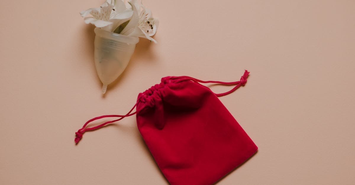 How to take care of Silicone cookware - Menstrual cup with white gentle flowers placed on pink surface near bag