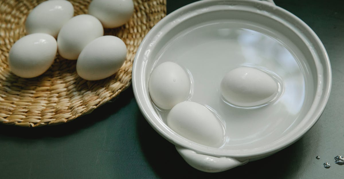 How to tell doneness of a boiled egg besides time - Boiled white chicken eggs in saucepan and wicker plate