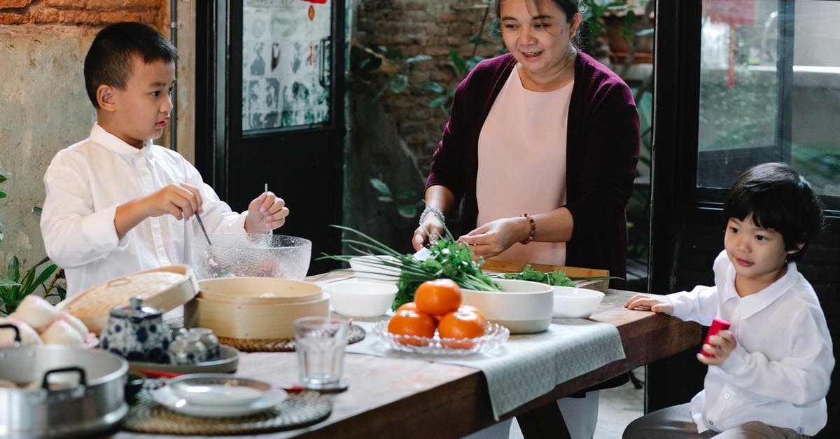 How to tell if a vegetable steamer contains titanium - Ethnic grandmother preparing ingredients for cooking traditional lunch while cooking with boys at table in kitchen