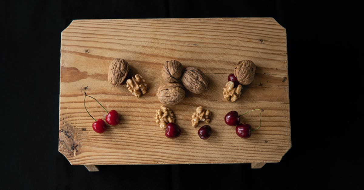 How to thin half and half to substitute for milk? - From above of crispy walnuts near sweet cherries on wooden table on black background