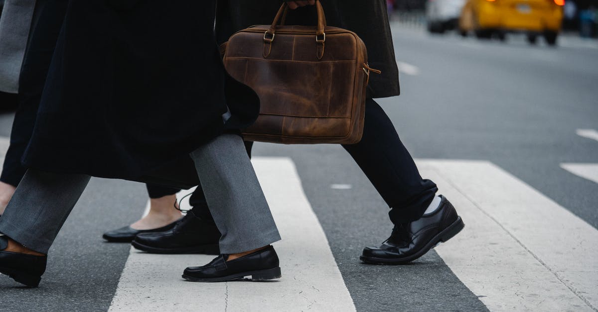 How to transport fresh ravioli to office potluck? - Side view of crop unrecognizable coworkers in formal wear with leather briefcase crossing urban road