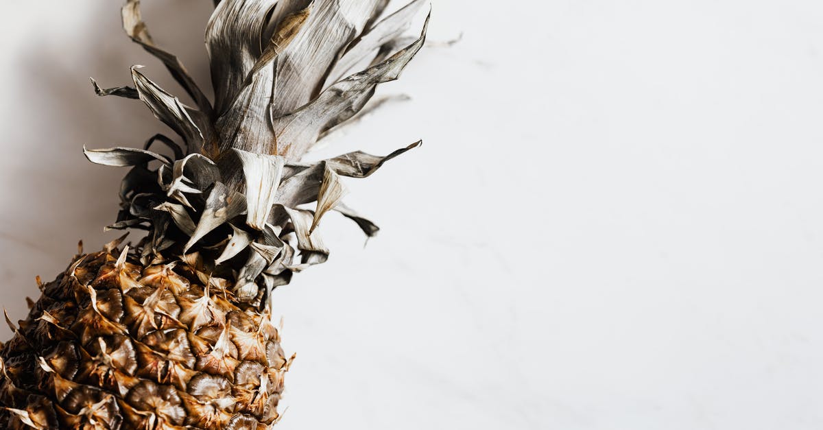 how to unstick dried pineapple chunks that are stuck together - Top view of ripe whole pineapple with dried crown placed on white background