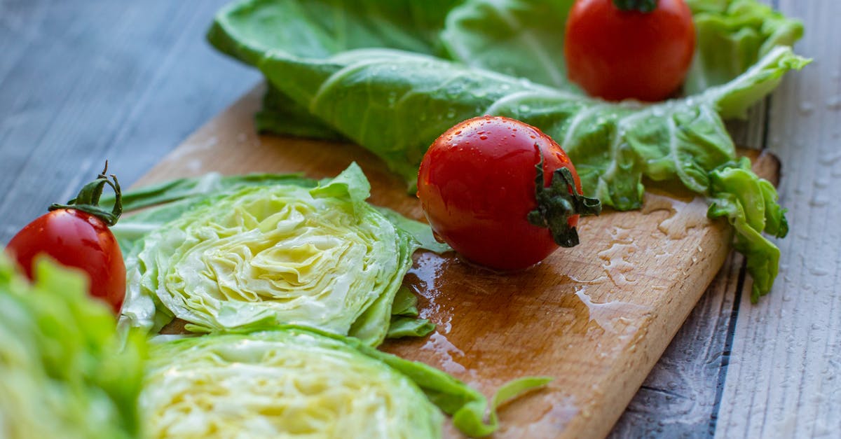 How to wash lettuce - From above of appetizing ripe red tomatoes and cut fresh cabbage placed on wet wooden chopping board in kitchen