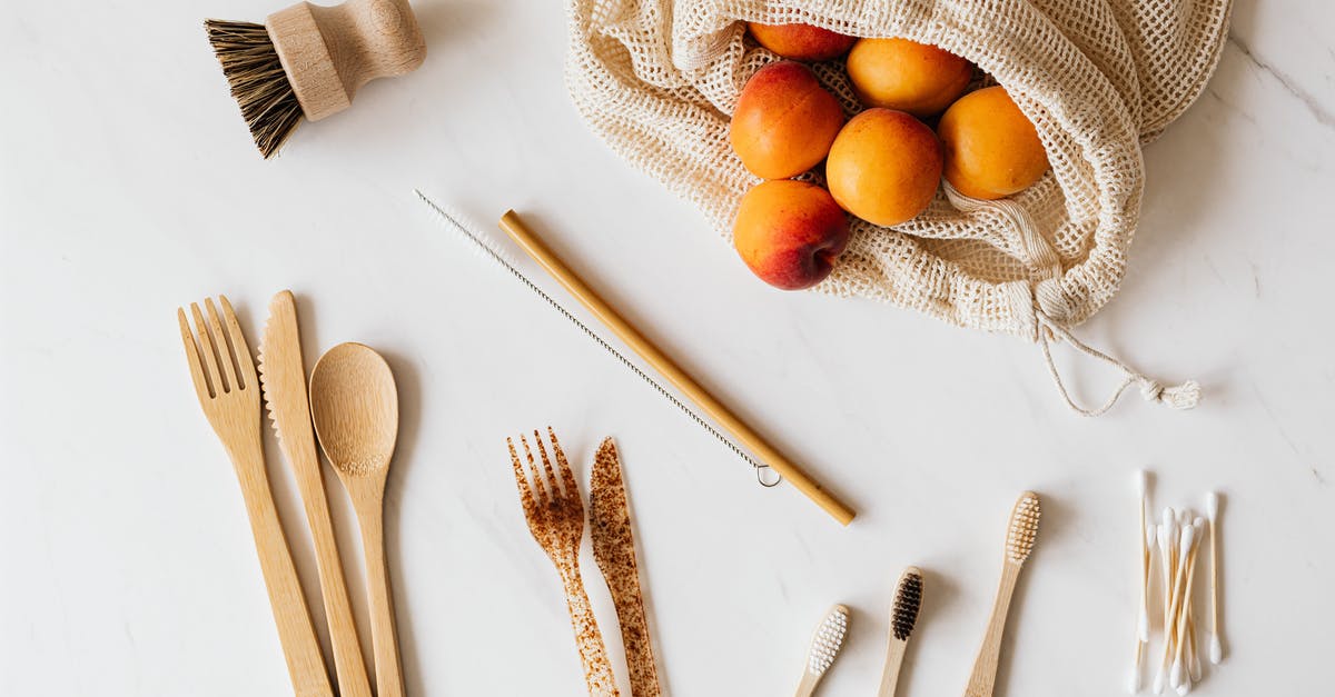 How to wash pesticides from fruit skins? - Bunch of delicious fresh peaches in cotton bag placed on table near wooden and plastic cutlery beside diverse wash accessories