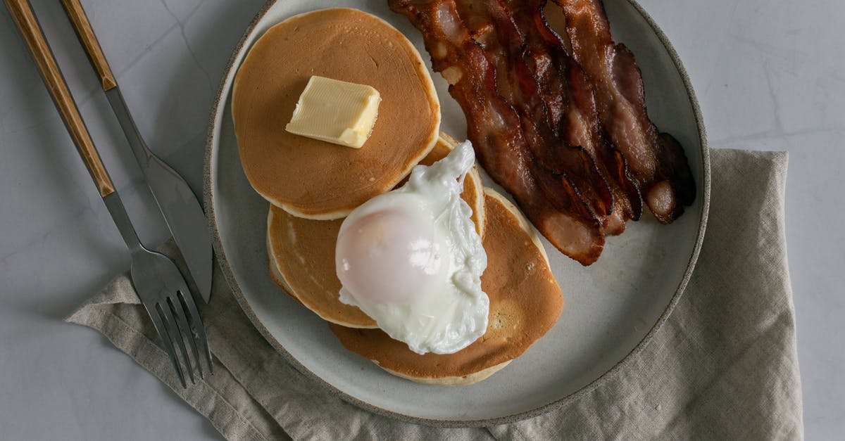 How would changing the amount of egg affect a pancake recipe? - Plate with pancakes with butter near roasted bacon and poached egg